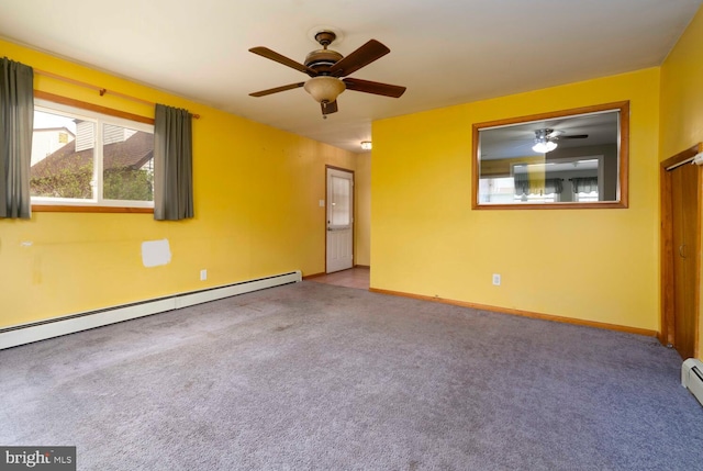 spare room with baseboard heating, carpet floors, a ceiling fan, and baseboards