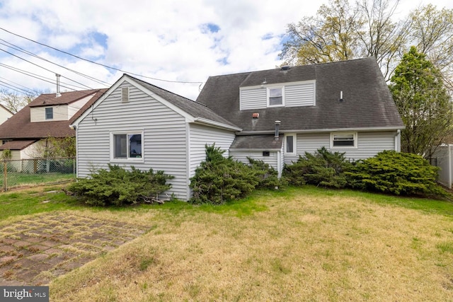 back of property featuring fence and a yard