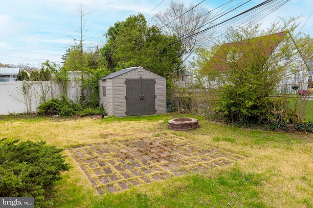 view of yard featuring a fire pit, an outbuilding, a shed, and a fenced backyard