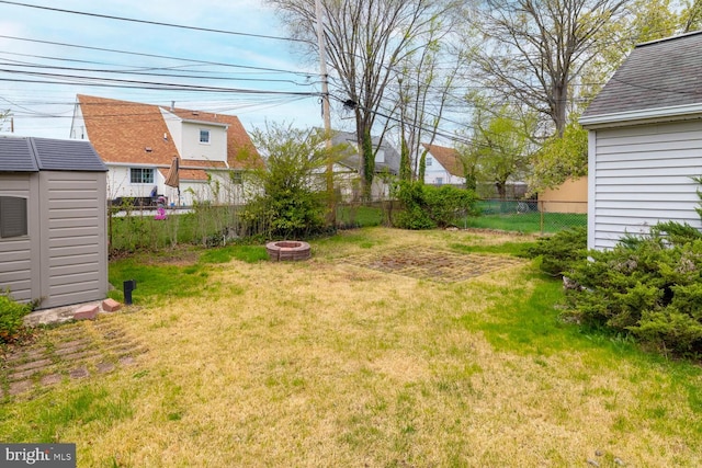 view of yard with a fenced backyard, an outdoor fire pit, an outdoor structure, and a storage unit