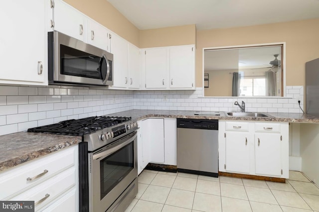 kitchen with tasteful backsplash, a sink, light tile patterned floors, stainless steel appliances, and white cabinets
