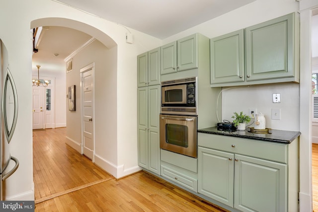 6218 30th St NW, Washington, DC 20015 - kitchen featuring stainless steel appliances, green cabinetry, arched walkways, light wood-style floors, and ornamental molding