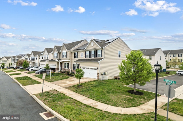 multi unit property featuring solar panels, a residential view, a front yard, concrete driveway, and an attached garage