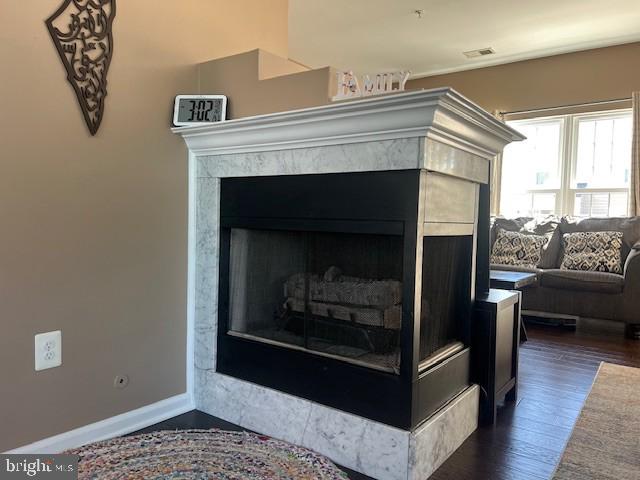room details featuring baseboards, visible vents, wood finished floors, and a fireplace