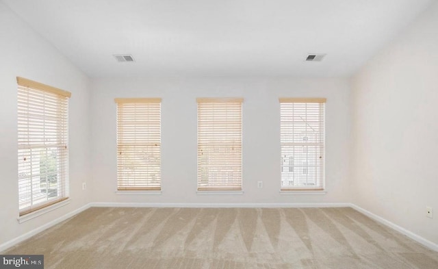 unfurnished room featuring light colored carpet, baseboards, and visible vents
