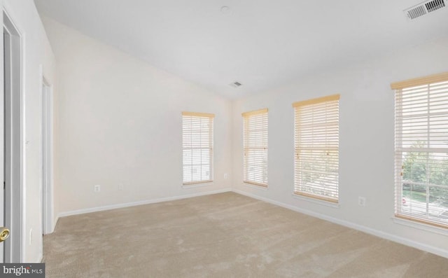 carpeted spare room with baseboards, vaulted ceiling, and visible vents