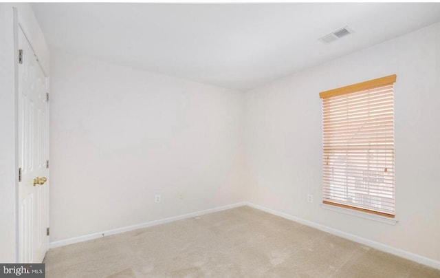 interior space with baseboards, visible vents, and light colored carpet