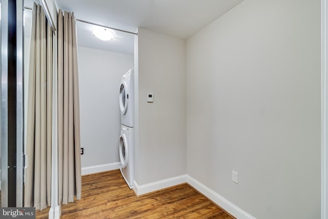 6301 Edsall Rd Unit 303, Alexandria, VA 22312 - clothes washing area featuring baseboards, wood finished floors, stacked washing maching and dryer, and laundry area