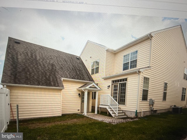 view of front of house featuring central AC unit, a shingled roof, and a front lawn