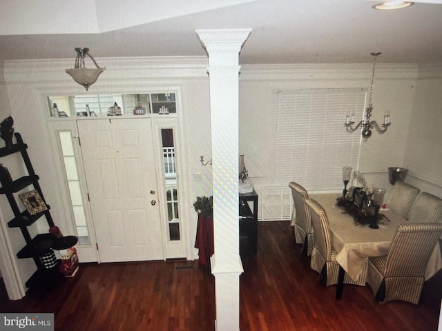 foyer featuring an inviting chandelier, wood finished floors, ornamental molding, and decorative columns