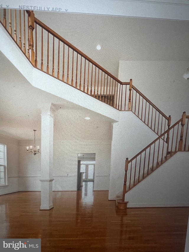 stairs featuring a towering ceiling, wood finished floors, and a notable chandelier
