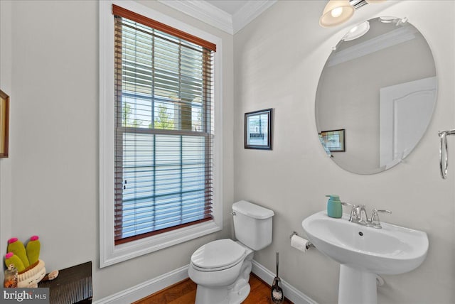 bathroom with wood finished floors, a sink, baseboards, toilet, and ornamental molding