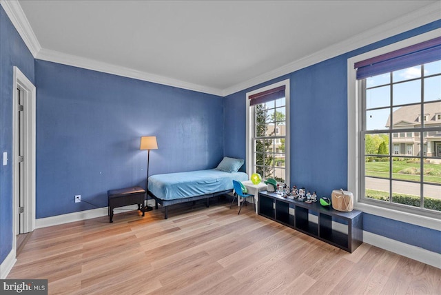 bedroom featuring baseboards, ornamental molding, and wood finished floors