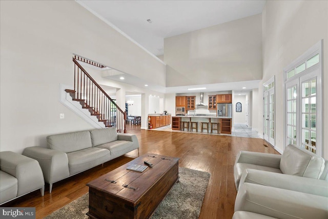 living area featuring light wood finished floors, stairway, and a towering ceiling