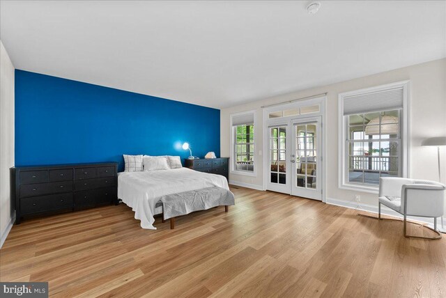 bedroom featuring light wood-style floors, baseboards, french doors, and access to exterior