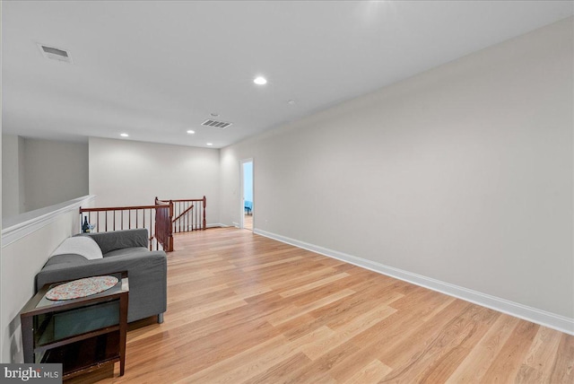 sitting room with visible vents, an upstairs landing, and light wood-type flooring