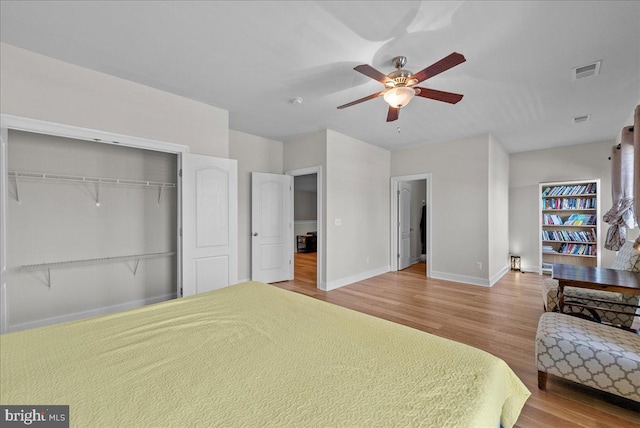 bedroom with visible vents, a closet, wood finished floors, baseboards, and ceiling fan