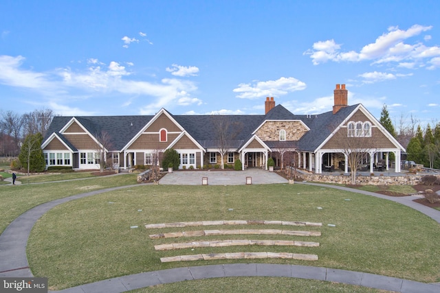 shingle-style home with a chimney, a front yard, and a porch