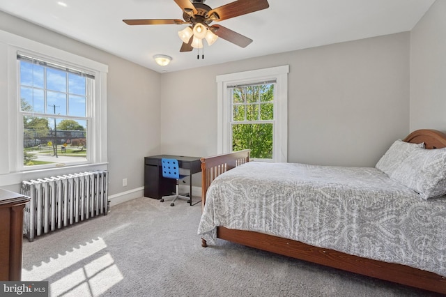 carpeted bedroom featuring radiator heating unit, baseboards, and a ceiling fan