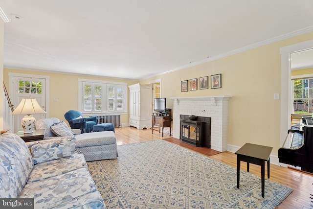 living room featuring a brick fireplace, ornamental molding, radiator heating unit, and wood finished floors