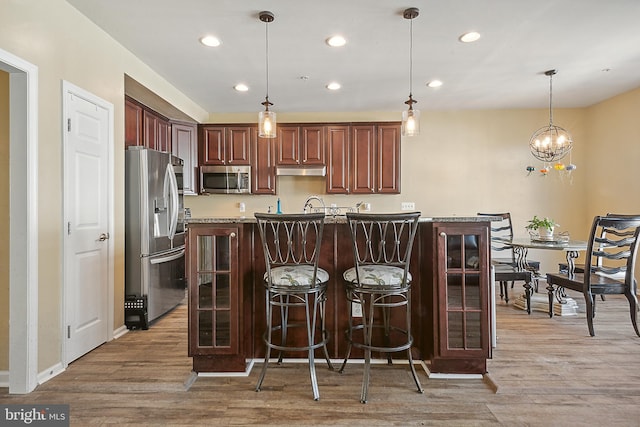 kitchen with recessed lighting, a breakfast bar area, stainless steel appliances, and light wood finished floors