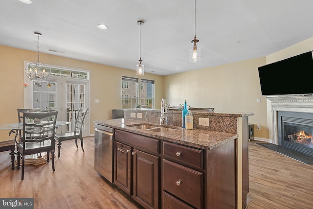 kitchen featuring dark brown cabinetry, a sink, light wood finished floors, dishwasher, and pendant lighting