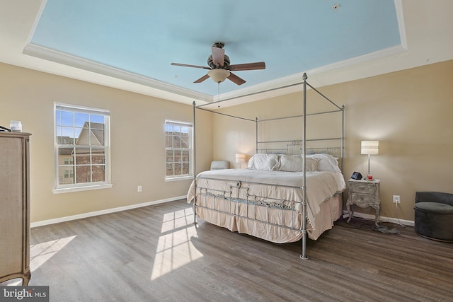 bedroom featuring baseboards, a tray ceiling, ceiling fan, and wood finished floors