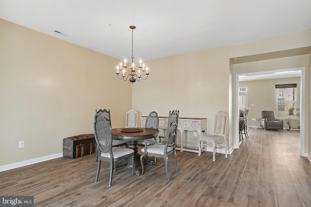 dining area featuring baseboards, wood finished floors, a notable chandelier, and visible vents
