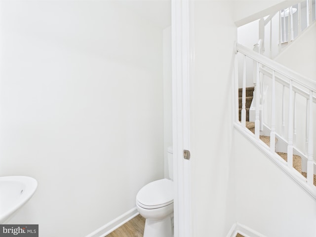 bathroom featuring wood finished floors, baseboards, and toilet