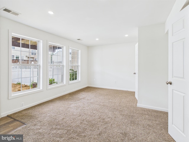 empty room with baseboards, recessed lighting, carpet flooring, and visible vents