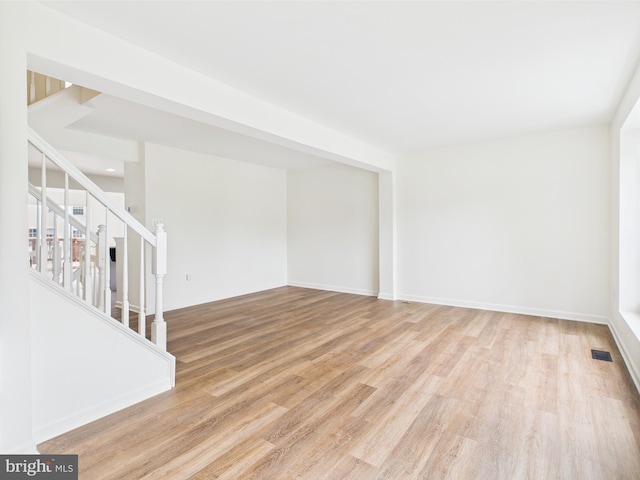 unfurnished living room with stairway, visible vents, and wood finished floors