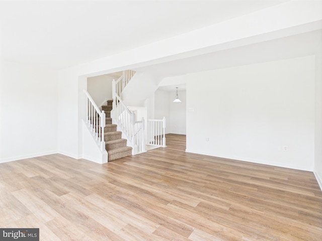 interior space featuring light wood finished floors, baseboards, and stairs