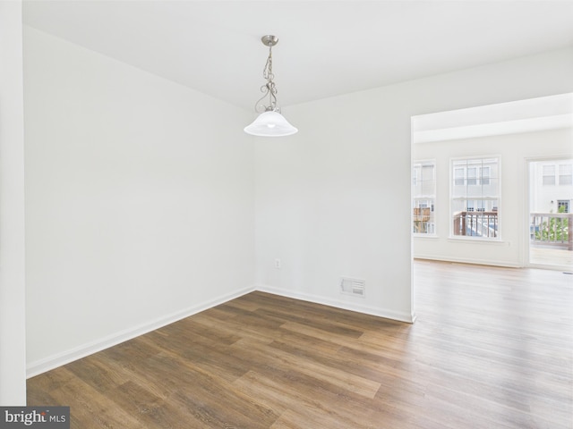unfurnished dining area with baseboards, visible vents, and wood finished floors