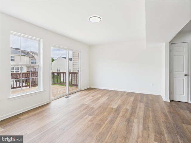 unfurnished room featuring baseboards, visible vents, and wood finished floors