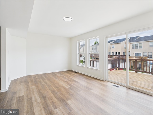 empty room with baseboards, visible vents, and wood finished floors