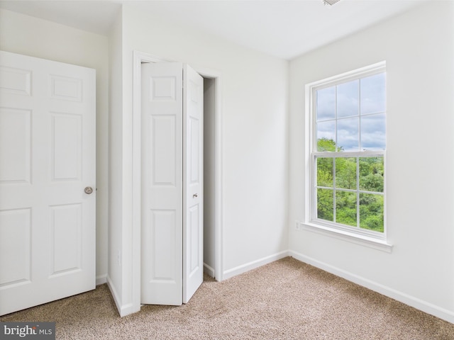 unfurnished bedroom with light colored carpet, a closet, and baseboards
