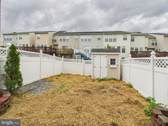 view of yard featuring a residential view, a fenced backyard, and a storage unit