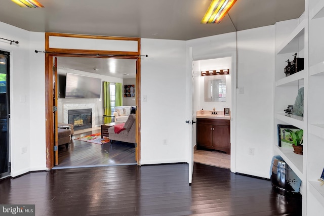 interior space featuring dark wood-style flooring, a premium fireplace, and baseboards