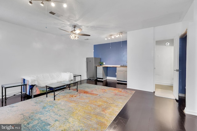 living room featuring visible vents, baseboards, dark wood-style flooring, track lighting, and a ceiling fan