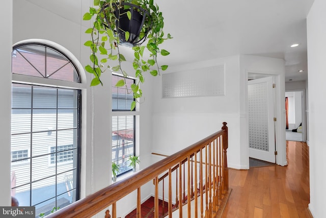 hall with an upstairs landing, hardwood / wood-style floors, recessed lighting, and baseboards