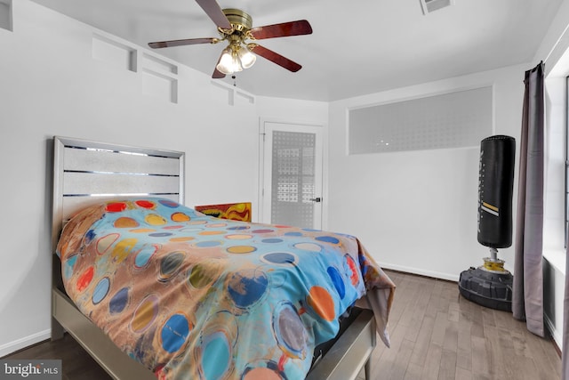bedroom with ceiling fan, wood finished floors, and baseboards
