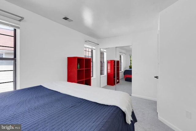 carpeted bedroom featuring visible vents, a closet, and baseboards