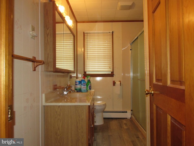 bathroom featuring wood finished floors, baseboard heating, toilet, vanity, and a stall shower