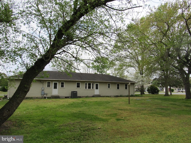 rear view of house with central AC, entry steps, and a yard