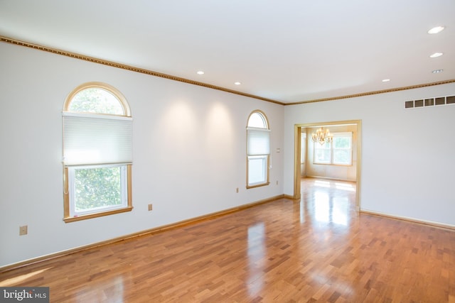 unfurnished room with a notable chandelier, ornamental molding, a healthy amount of sunlight, and visible vents