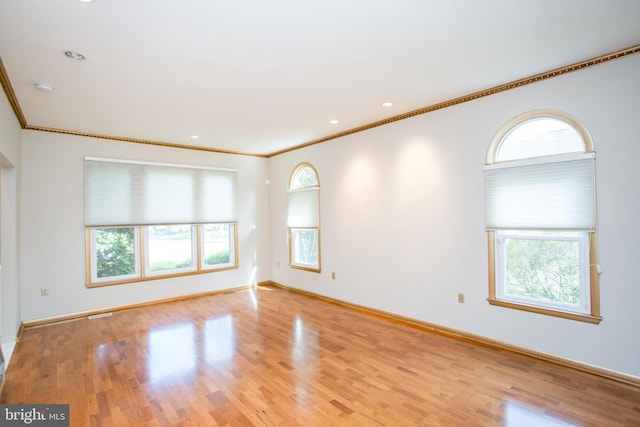 spare room featuring crown molding, baseboards, and wood finished floors