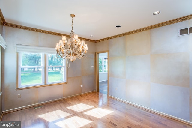 unfurnished dining area with visible vents, crown molding, wood finished floors, and a notable chandelier