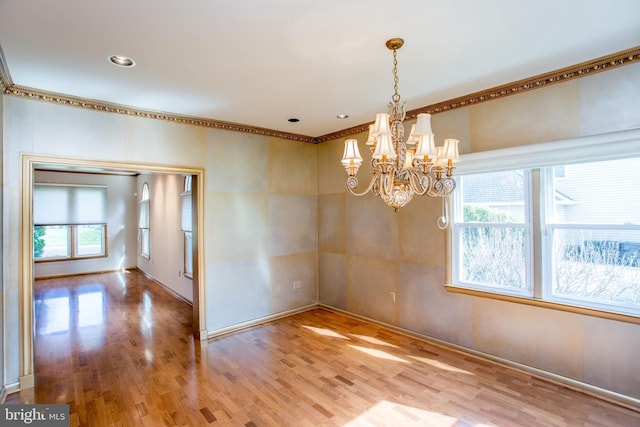 unfurnished room featuring baseboards, a chandelier, ornamental molding, and wood finished floors