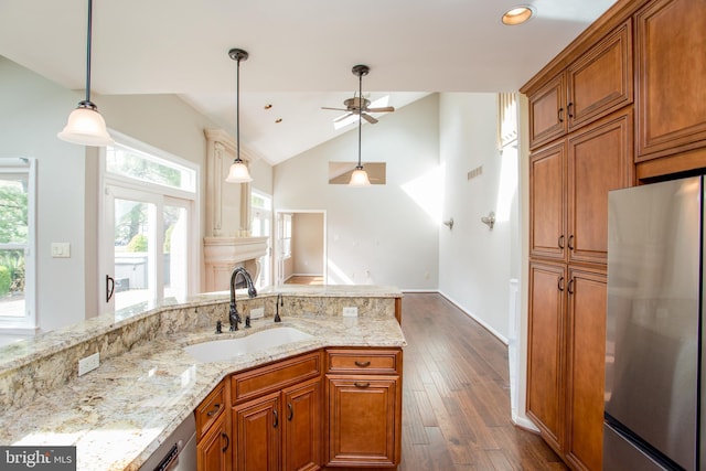 kitchen featuring stainless steel appliances, a ceiling fan, brown cabinetry, and a sink