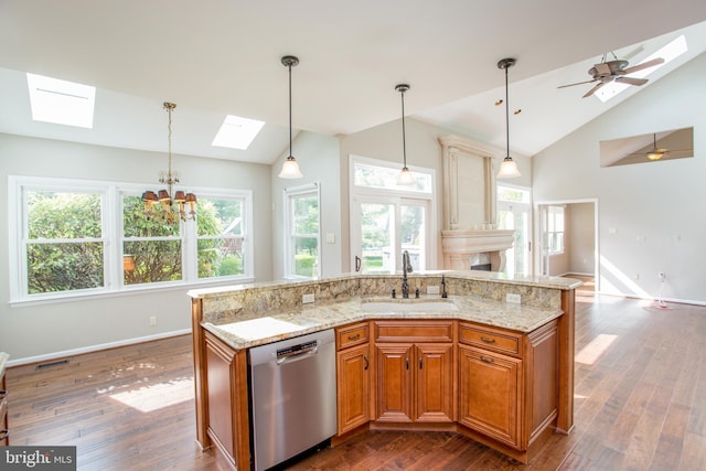 kitchen with a sink, baseboards, stainless steel dishwasher, and lofted ceiling with skylight